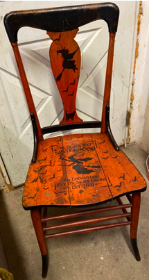 Antique wooden chair painted orange and black with halloween themed stenciling