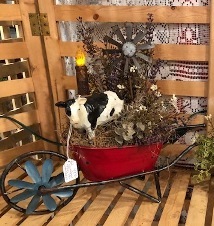 Cow in a red wheelbarrow with a windmill and light