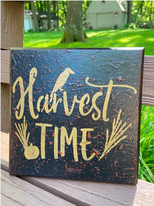 Black wooden sign with a crown on it that says Harvest Time